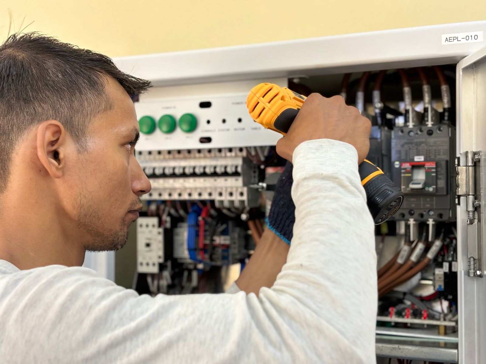 An electrician working carefully at an electrical panel
