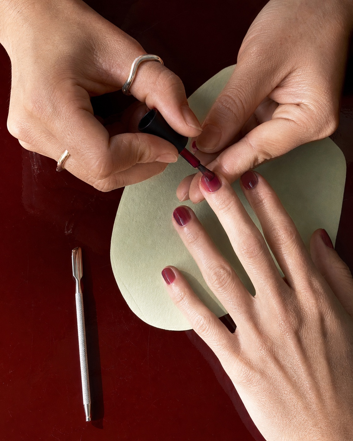 A manicure in progress on an oxblood work surface